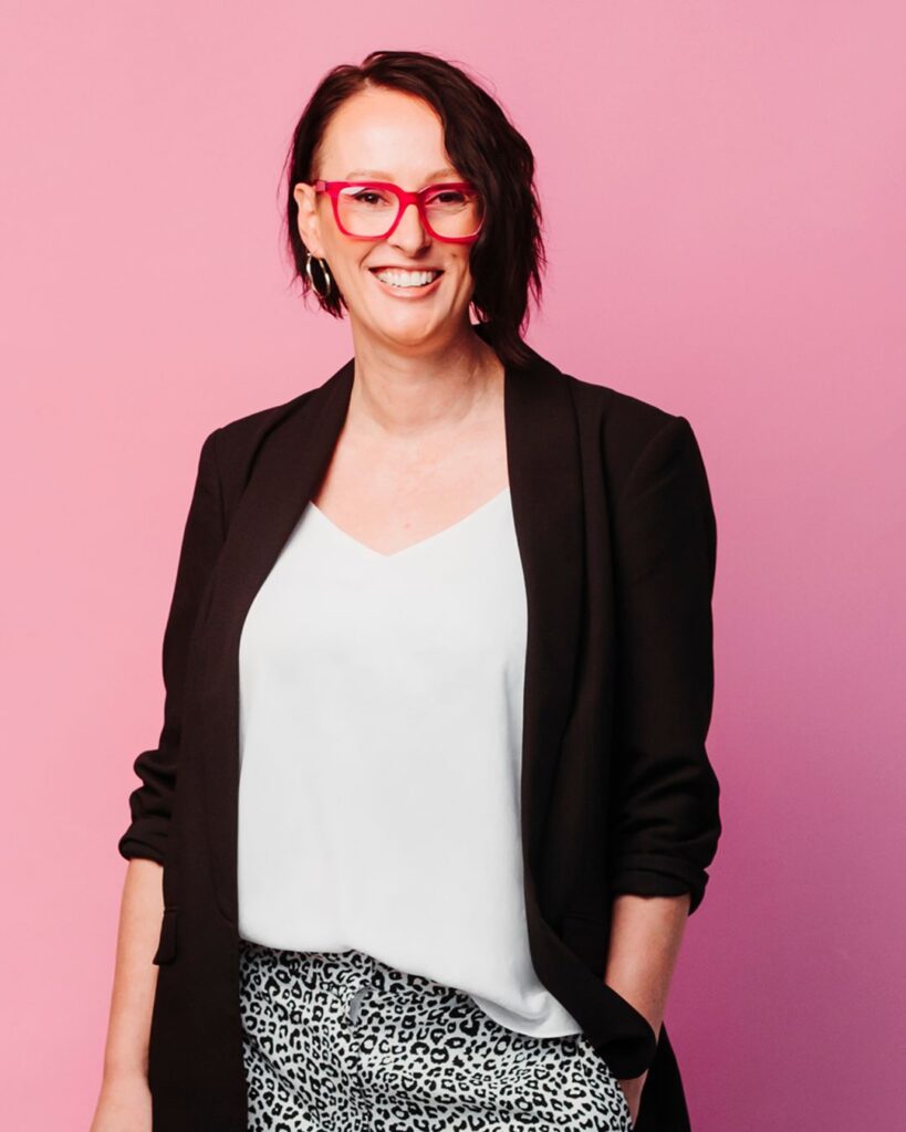 Marketing with A Alicia Montesano Copywriter standing wearing pink glasses black jacket